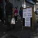 Los peatones pasan frente a un cartel que muestra los precios del producto en bolívares, en Caracas, Venezuela.