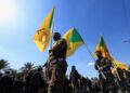 Miembros del grupo armado iraquí Kataib Hezbollah sostienen banderas durante el funeral de sus miembros, el 2 de marzo de 2026 (REUTERS/Thaier Al-Suda)