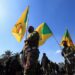 Miembros del grupo armado iraquí Kataib Hezbollah sostienen banderas durante el funeral de sus miembros, el 2 de marzo de 2026 (REUTERS/Thaier Al-Suda)